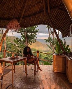 a woman sitting at a table on top of a wooden deck