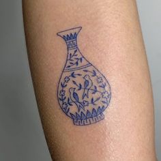 a blue and white vase tattoo on the arm