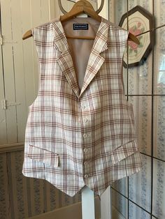 This beautiful vest from Paul Fredrick is made from 100 per cent linen in a plaid pattern, in ivory off white, light beige and light brown. It has the original buttons and two front pockets. The back and lining are made from a light golden brown silky fabric. Marked size 46. The measurements, taken with the vest lying flat, are: shoulder to shoulder, 15 inches; armpit to armpit, 24 inches; length, 28 inches in front and 25 inches in back; bottom edge, 24 inches. In very good condition. Fitted Plaid Cotton Vest, Classic Plaid Vest, Classic Plaid Sleeveless Vest, Classic Sleeveless Plaid Vest, Vintage Beige Workwear Vest, Classic Beige Vest For Summer, Fitted Beige Linen Vest, Light Golden Brown, Beige Plaid