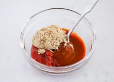 a glass bowl filled with sauce and crumbs on top of a white counter