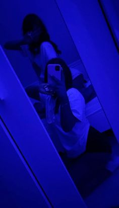 a woman taking a selfie in the bathroom with her cell phone and blue light