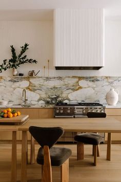 a modern kitchen with marble counter tops and wooden chairs in front of the stove top