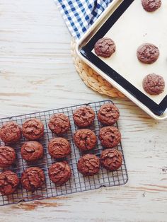 chocolate cookies cooling on a wire rack next to a baking tray and cookie sheet with more cookies in it