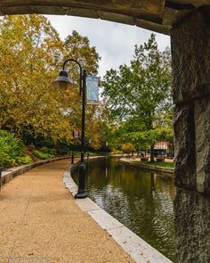 an arch in the middle of a walkway leading to a pond