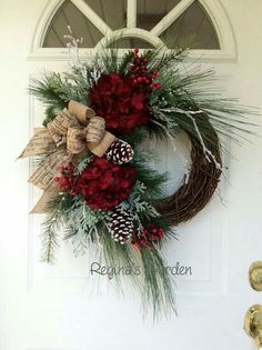 a wreath with pine cones and red flowers on the front door is decorated with burlap