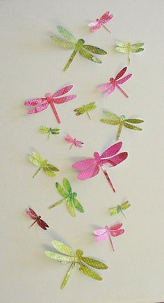 a group of dragonflys that are on a white surface with pink, green and yellow colors