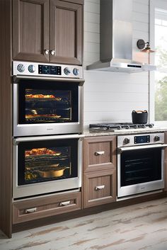 two ovens in a kitchen with wood cabinets and white tile flooring on the walls