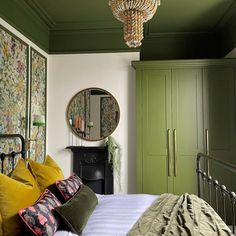 a bedroom with green walls and white bedding has a chandelier hanging from the ceiling