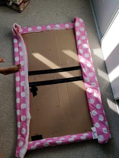 a pink and white polka dot frame sitting on the floor next to a cardboard box