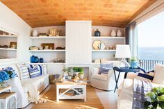 a living room filled with white furniture and lots of blue decor on top of it