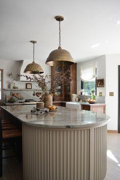 a kitchen with an island and two pendant lights hanging from it's ceiling over the counter