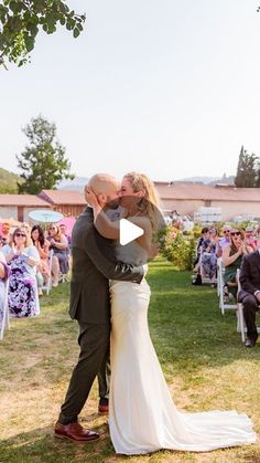 a bride and groom kissing in front of an outdoor wedding ceremony with people watching them