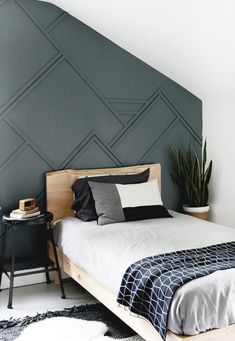 a bed sitting in a bedroom next to a wall with geometric designs on it's headboard