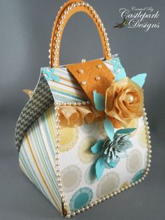 an origami purse with flowers on the front and side, sitting on a gray background