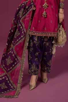 Maria B Raw Silk Salwar Kameez Pakistani Party Dress is a traditional attire that will give you a stunning look on the festive occasion. The kameez is beautifully embellished with tilla, sequins, embroidery, and pearls. Embellished borders and neckline give a perfect finishing to the kameez. The Salwar has an alluring purple shade that gives a lavish contrast to the attire. An embellished organza dupatta completes the overall look of this Pakistani Party Wear. Detailed Description: SKU: PS2406 Detailing: Embroidery, Motifs, Sequins, Pearls, Cutwork, Crystals, Stones, Tilla Color: Pink, Purple Fabric: Organza, Raw silk Design: Fully Embellished Dress with Embroidery, Tilla Event: Bridal wear, Wedding Brinjal Colour Combination Dress, Mendhi Dresses, Raw Silk Salwar, Fabric Study, Frock Suit, Gharara Designs, Salwar Kameez Pakistani, Silk Design, Pakistani Party Wear