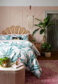 a tropical themed bedroom with pink walls and palm leaves on the bed, along with potted plants