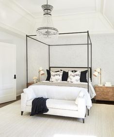 a bedroom with a four poster bed and chandelier hanging from it's ceiling