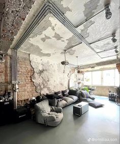 a living room filled with lots of furniture next to a wall covered in peeling paint