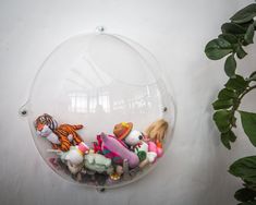 there is a glass bowl with stuffed animals in it on the wall next to a potted plant