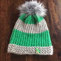 a green and white knitted hat with a pom - pom on top