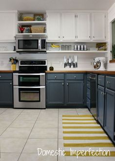 a kitchen with gray cabinets and white walls, yellow rugs on the floor in front of the stove