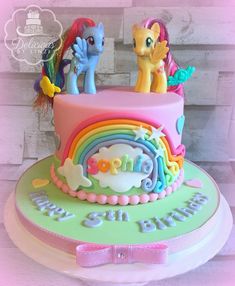 a birthday cake decorated with rainbows and ponies