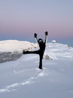 a person standing on top of a snow covered slope with their arms in the air