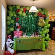 a table with green balloons and presents on it in front of a dr seuss balloon wall