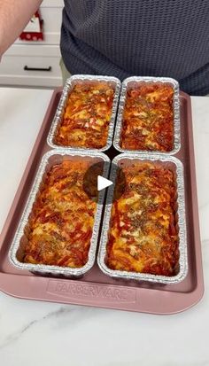 four pans filled with lasagna sitting on top of a white countertop