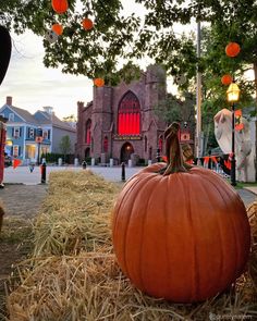 pumpkins and hay bales in front of a building with orange lights hanging from it