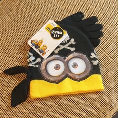 a black and yellow hat with googly eyes on top of a table next to a pair of eyeglasses