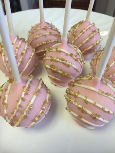 pink and white cake pops with gold sprinkles on a white platter