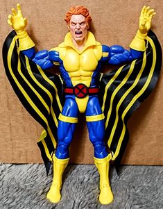 the action figure is posed in front of a cardboard box and has his arms spread out