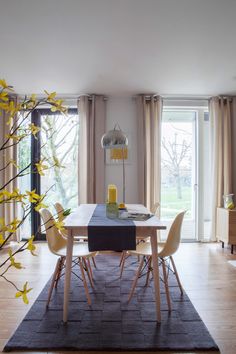 a dining room table with chairs and a rug on the floor in front of it