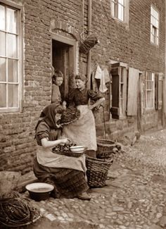 an old photo of two women in front of a brick building with laundry hanging out to dry