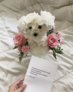 someone is holding a card with flowers and a teddy bear