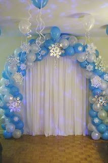 an arch made out of balloons and snowflakes is decorated with blue streamers