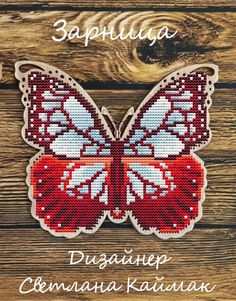 a cross stitch butterfly sitting on top of a wooden table