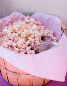 a bowl filled with rice sitting on top of a purple tablecloth covered floor next to a metal spoon