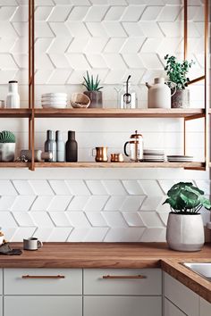 a kitchen with white hexagonal tiles on the wall and wooden counter tops, potted houseplants and other items