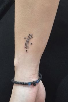 a woman's wrist with a small star tattoo on the left side of her arm