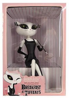 a black and white cat doll in a pink box with the caption breakfast at tiffany's