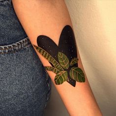 a woman's arm with a leaf tattoo on it