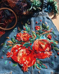 an embroidered jean skirt with flowers and leaves on the side, next to a basket of yarn