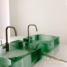 two green glass sinks sitting next to each other on top of a white countertop