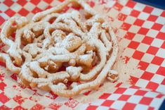 a pastry is covered with powdered sugar on a red and white checkered tablecloth