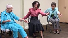 three older women sitting in chairs with one holding her hand out