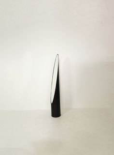 a black and white vase sitting on top of a table next to a white wall