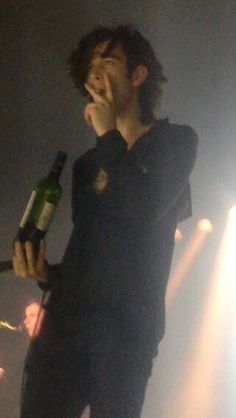 a man holding a wine bottle in his right hand and looking up at the sky