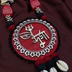 a red and black necklace with an omen symbol on it